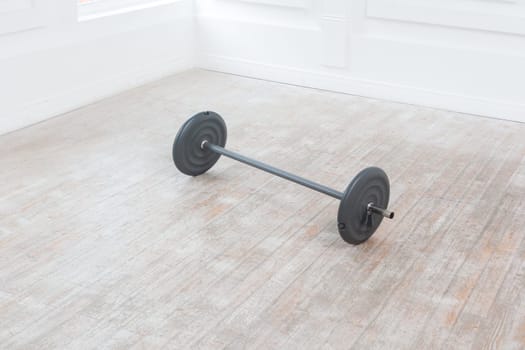 Heavy barbell on floor in gym on white wall background. Sport equipment. Indoor studio shot.
