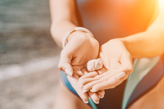 Beach vacation snapshot: A woman in a swimsuit holding a pebble in her hands, enjoying the serenity of the beach and the beauty of nature, creating a peaceful and relaxing atmosphere