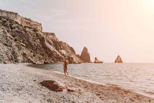 Woman travel summer sea. A happy tourist in a blue bikini enjoying the scenic view of the sea and volcanic mountains while taking pictures to capture the memories of her travel adventure