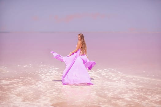 Woman pink salt lake. Against the backdrop of a pink salt lake, a woman in a long pink dress takes a leisurely stroll along the white, salty shore, capturing a wanderlust moment