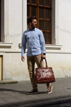 Handsome businessman walking on the street, with luxury leather briefcase. Fashionable style. Street photo