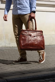 Handsome businessman walking on the street, with luxury leather briefcase. Fashionable style. Street photo