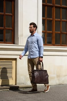 Handsome businessman walking on the street, with luxury leather briefcase. Fashionable style. Street photo