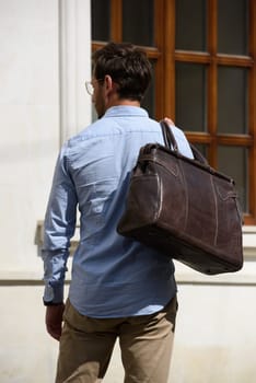 Handsome businessman walking on the street, with luxury leather briefcase. Fashionable style. Street photo