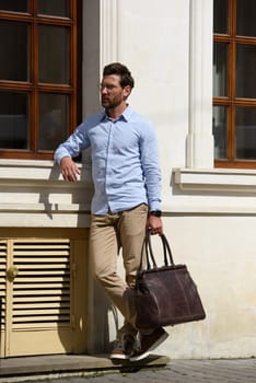 Handsome businessman walking on the street, with luxury leather briefcase. Fashionable style. Street photo