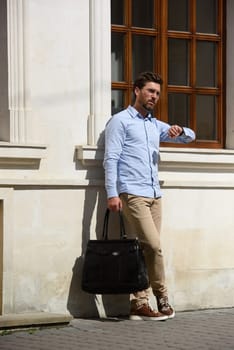 Handsome businessman walking on the street, with luxury leather briefcase. Fashionable style. Street photo