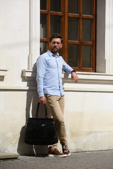 Handsome businessman walking on the street, with luxury leather briefcase. Fashionable style. Street photo