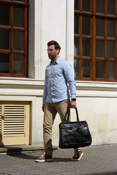 Handsome businessman walking on the street, with luxury leather briefcase. Fashionable style. Street photo