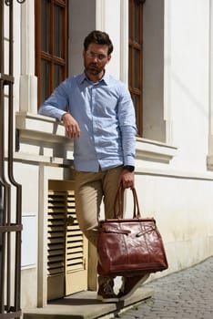 Handsome businessman walking on the street, with luxury leather briefcase. Fashionable style. Street photo