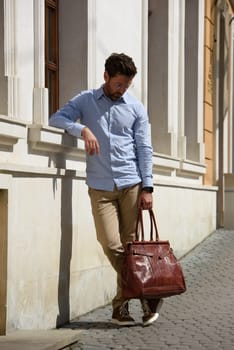 Handsome businessman walking on the street, with luxury leather briefcase. Fashionable style. Street photo