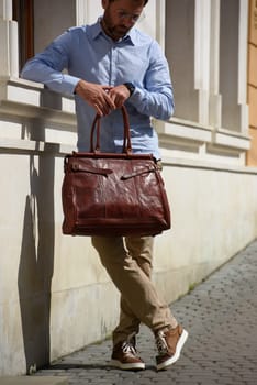 Handsome businessman walking on the street, with luxury leather briefcase. Fashionable style. Street photo