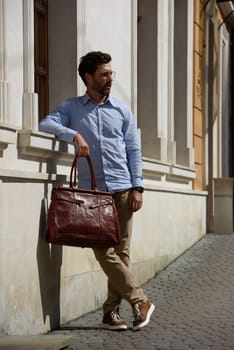 Handsome businessman walking on the street, with luxury leather briefcase. Fashionable style. Street photo