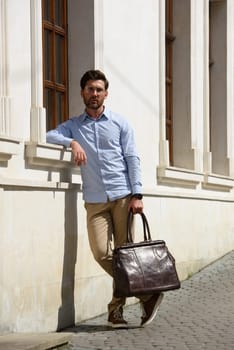 Handsome businessman walking on the street, with luxury leather briefcase. Fashionable style. Street photo