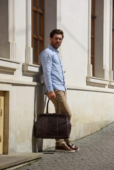 Handsome businessman walking on the street, with luxury leather briefcase. Fashionable style. Street photo