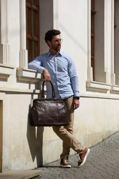 Handsome businessman walking on the street, with luxury leather briefcase. Fashionable style. Street photo