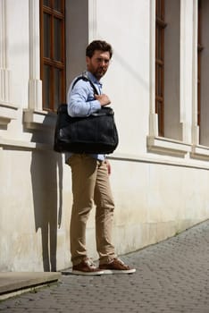 Handsome businessman walking on the street, with luxury leather briefcase. Fashionable style. Street photo