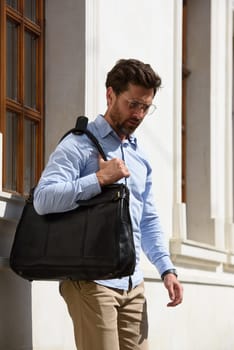 Handsome businessman walking on the street, with luxury leather briefcase. Fashionable style. Street photo