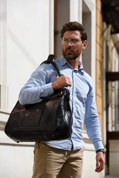 Handsome businessman walking on the street, with luxury leather briefcase. Fashionable style. Street photo