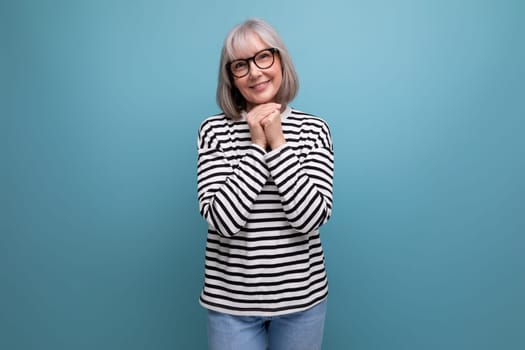 close-up portrait of an old woman with gray hair smiling kindly against a bright studio background.