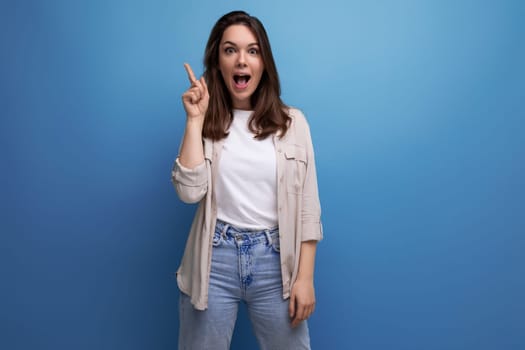 inspired smart brunette young woman in a stylish look owns information on a blue background with copy space.