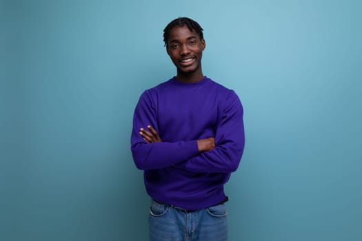 charming dark-skinned young brunette man with dreadlocks in a blue sweatshirt.