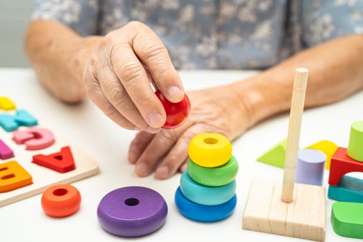 Alzheimer disease AD, Asian elderly woman patient suffering from dementia learn practical motor skills rehabilitation.