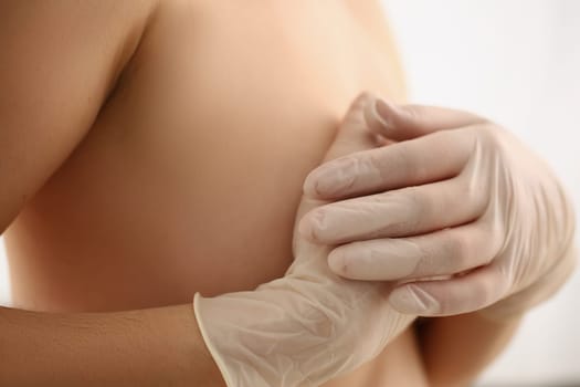 Young woman examines breasts, cancer prevention closeup. Mammoplasty and breast diagnostics