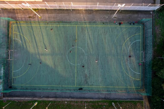 Aerial drone top view of mini football soccer field with artificial plastic cover with playing people. Public sport ground in city at sunny summer day drone view. Portugal