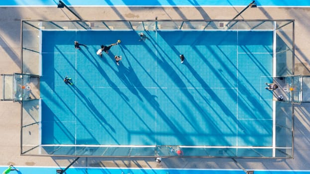 Aerial view of blue multi-sport court in public park. Used to practice football, basketball. Top view. Sunny day. Sunset. Drone photo.