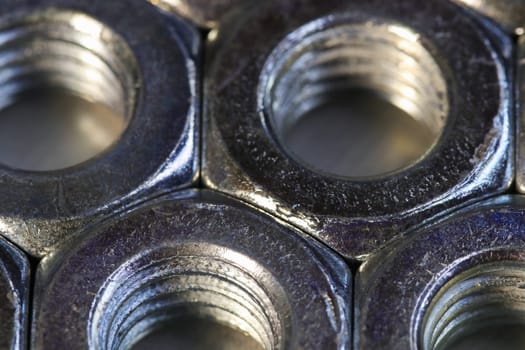 Macro close-up of tightly packed threaded steel hex nut fasteners