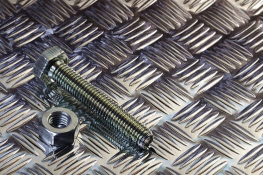 Threaded hex nut and bolt on clean metal tread plate surface