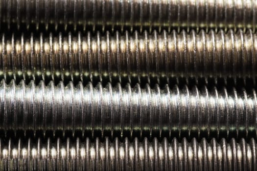 Tightly packed threaded steel bolts screw thread detail close-up