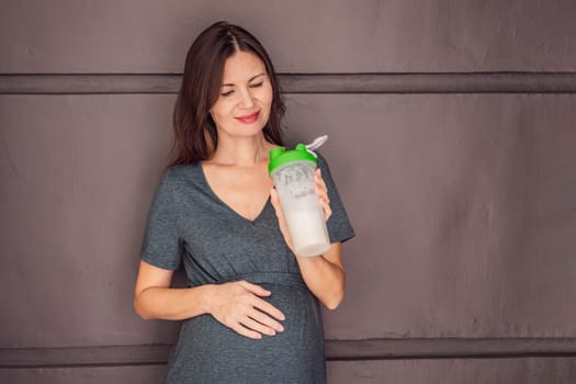 Energetic and fit pregnant woman after 40 enjoying a protein shake for a nourishing boost during her pregnancy journey. Embracing health and wellness for a thriving baby and mom.