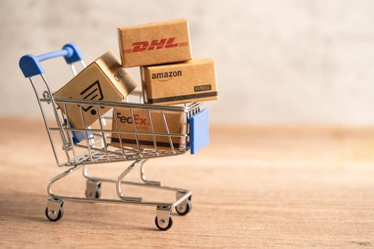 Bangkok, Thailand September 26, 2022 Shopping cart with DHL Amazon and FedEx express packing box, import export online exchange investment business.