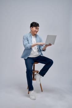 Young Asian business man sitting on chair and using laptop on background
