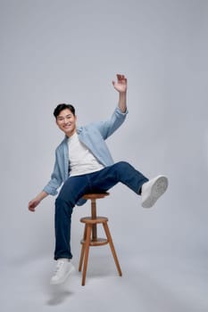 Photo portrait young man smiling sitting on wooden chair isolated on white background