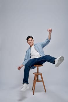 Full length of a cheerful young man sitting on chair and celebrating success 