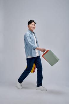 A portrait of happy young asian man holding shopping bags, full body