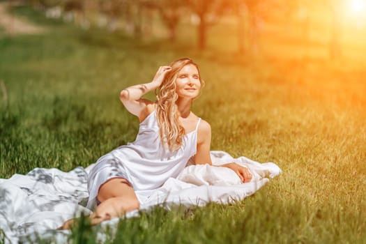 woman garden. she sleeps on a white bed in the fresh spring grass in the garden. Dressed in a blue nightgown