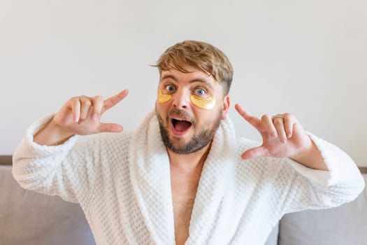 Beauty treatments, skin care, metrosexual concept. A handsome bearded man with golden bandages under his eyes makes funny faces with facial expressions.