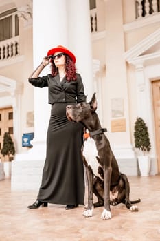 A photo of a woman and her Great Dane walking through a town, taking in the sights and sounds of the urban environment.