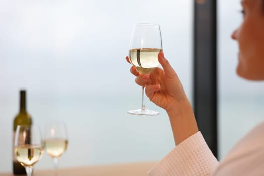 Lonely woman drinks wine alone in hotel room. Female alcoholism