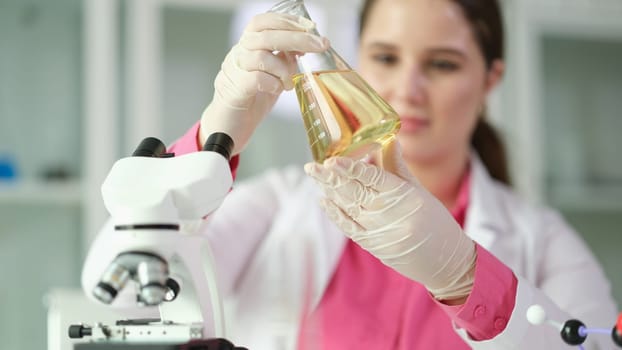 Researcher scientist student holding flask with yellow liquid. Studying properties of oil and oil products