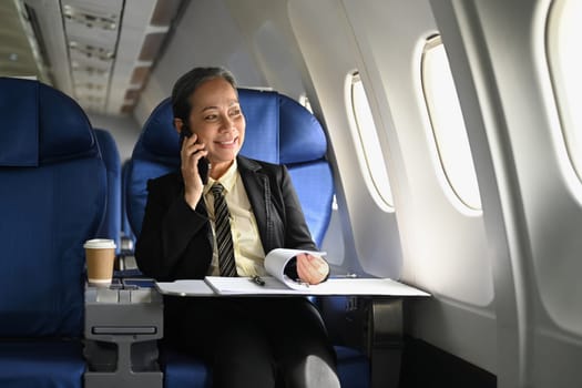 Beautiful middle age businesswoman working with document in aircraft during business travel.