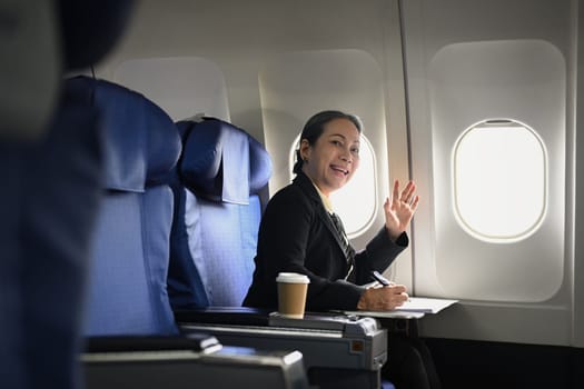 Beautiful middle age businesswoman working with document in aircraft during business travel.