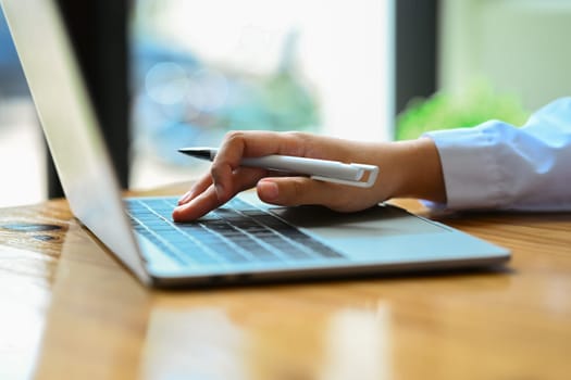 Side view of female worker hand typing on laptop, searching information, browsing internet, working online.