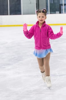 Little girl practicing figure skating on an indoor ice rink.