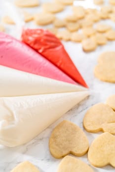 Decorating heart-shaped sugar cookies with pink and white royal icing for Valentine's Day.