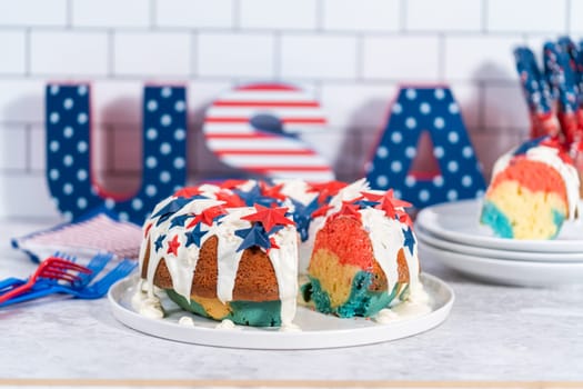 Slicing July 4th bundt cake covered with a vanilla glaze and decorated with chocolate stars.