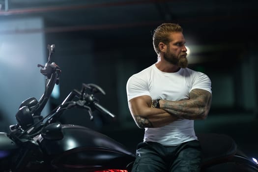 Sexy handsome attractive sporty muscular fitness model breaded biker in white tight tshirt sits on brutal beautiful motorcycle in the parking